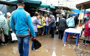 Оренбуржцы закупаются на рынке, шлепая по грязи